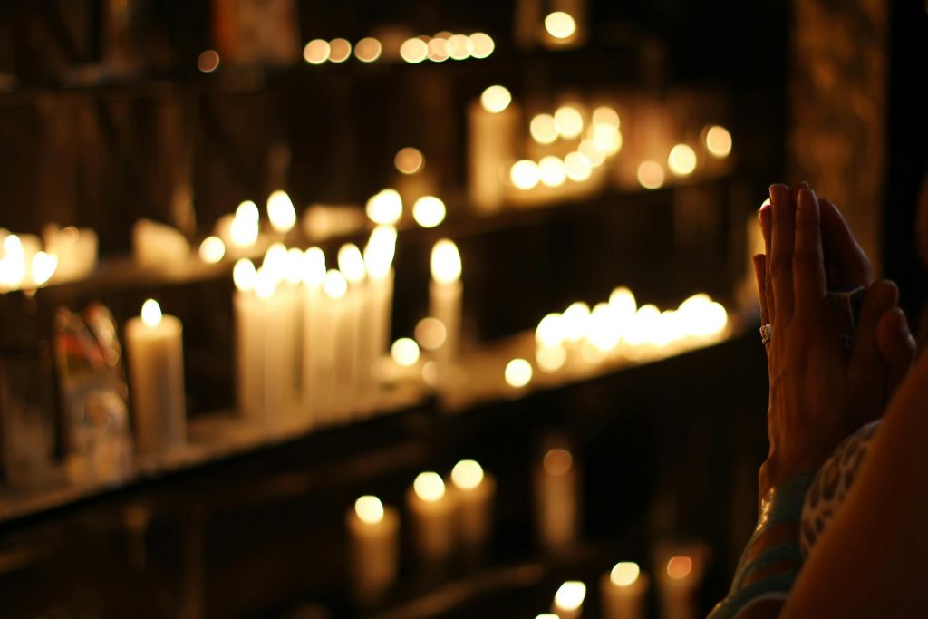 Someone praying while surrounded by lit candles