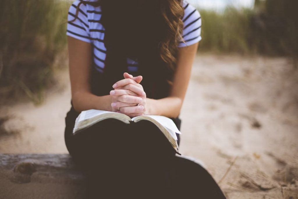 Woman Praying With Hands Together on Bible